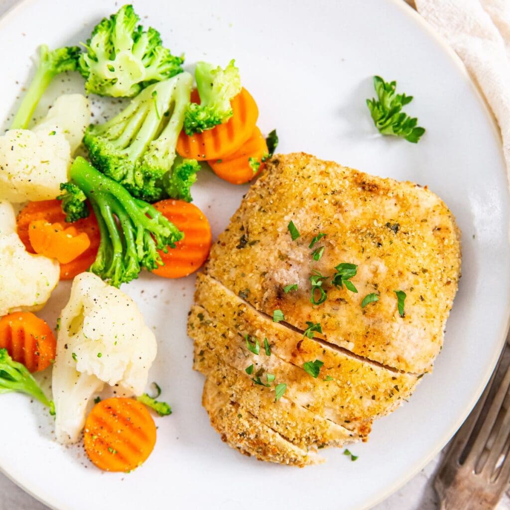 white plate with chicken and vegetables on it