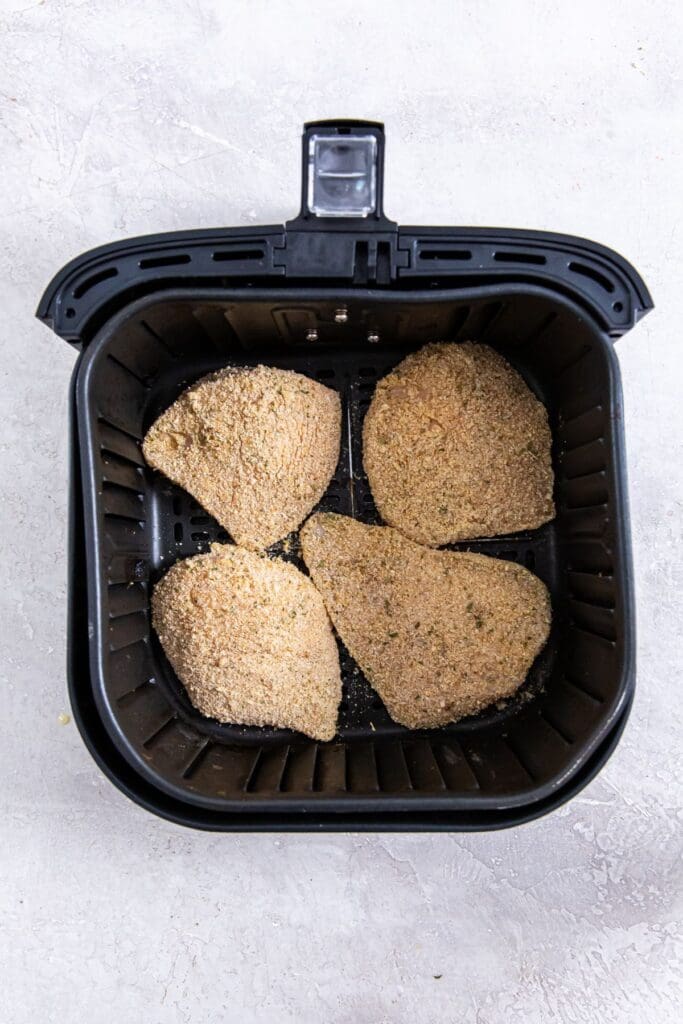 black air fryer basket with raw chicken inside