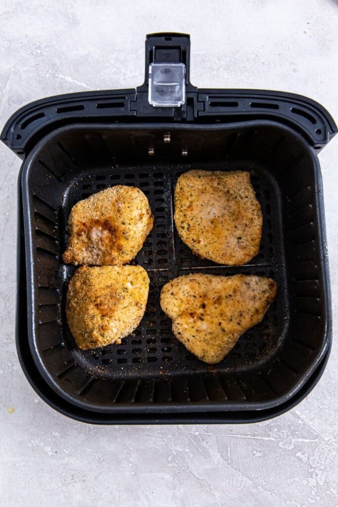 black air fryer basket with cooked chicken inside