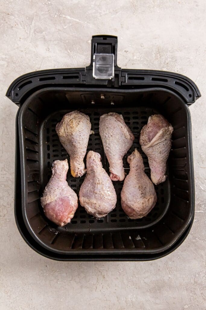 black air fryer basket with raw chicken inside