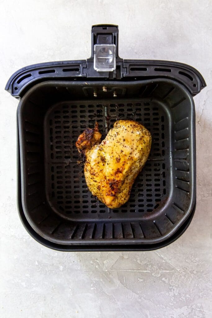 An air fryer perfectly cooking lemon pepper chicken breasts.