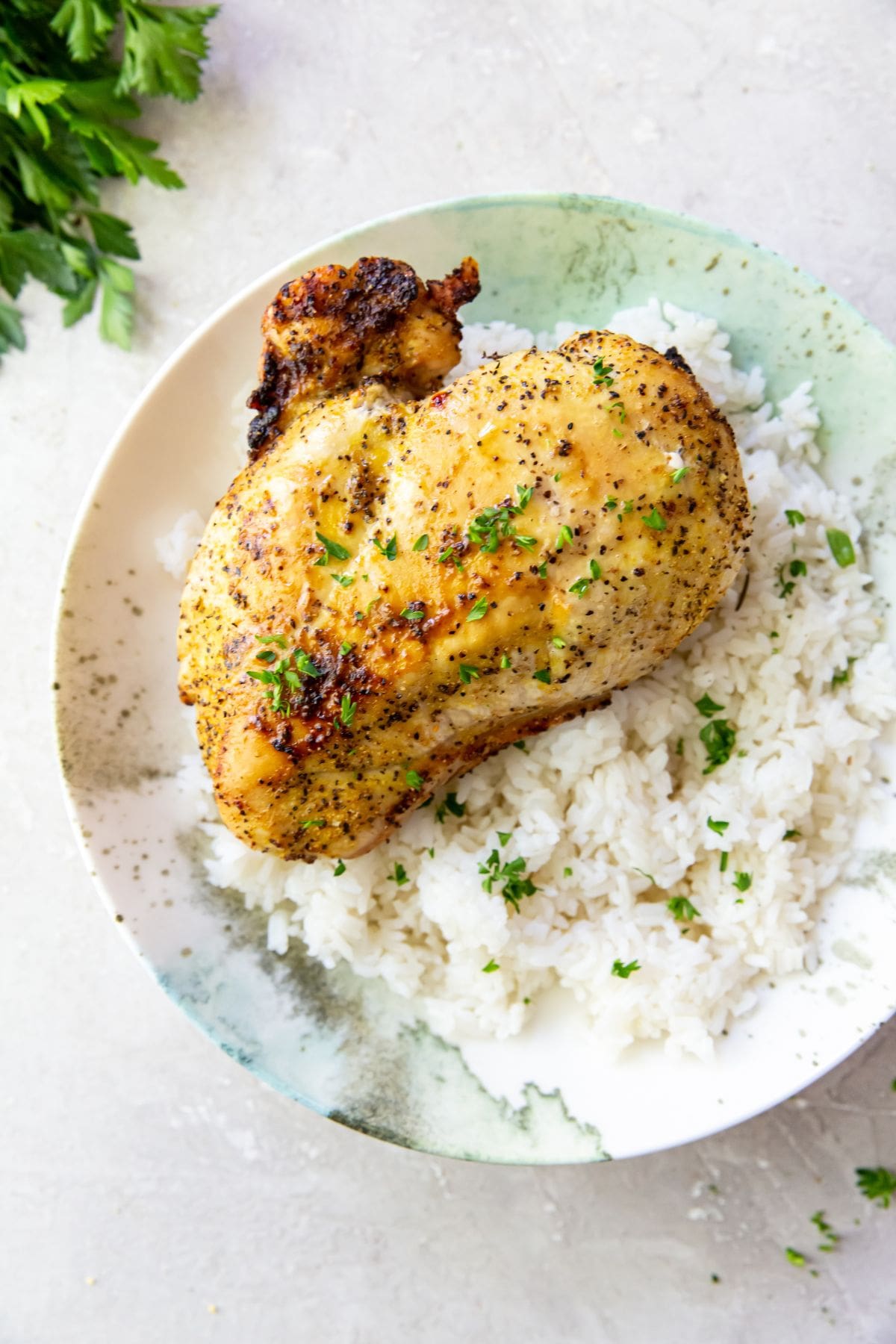 A plate of chicken breasts served with rice and parsley.