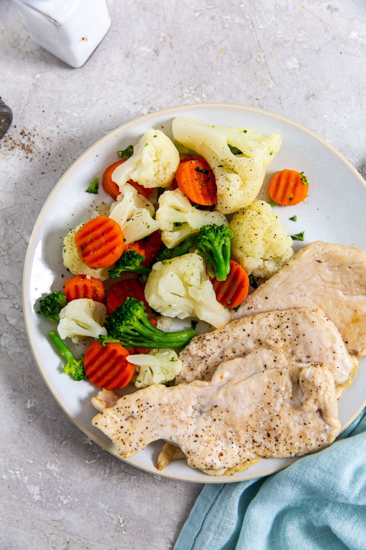 A plate with sliced chicken breast and vegetables on it.