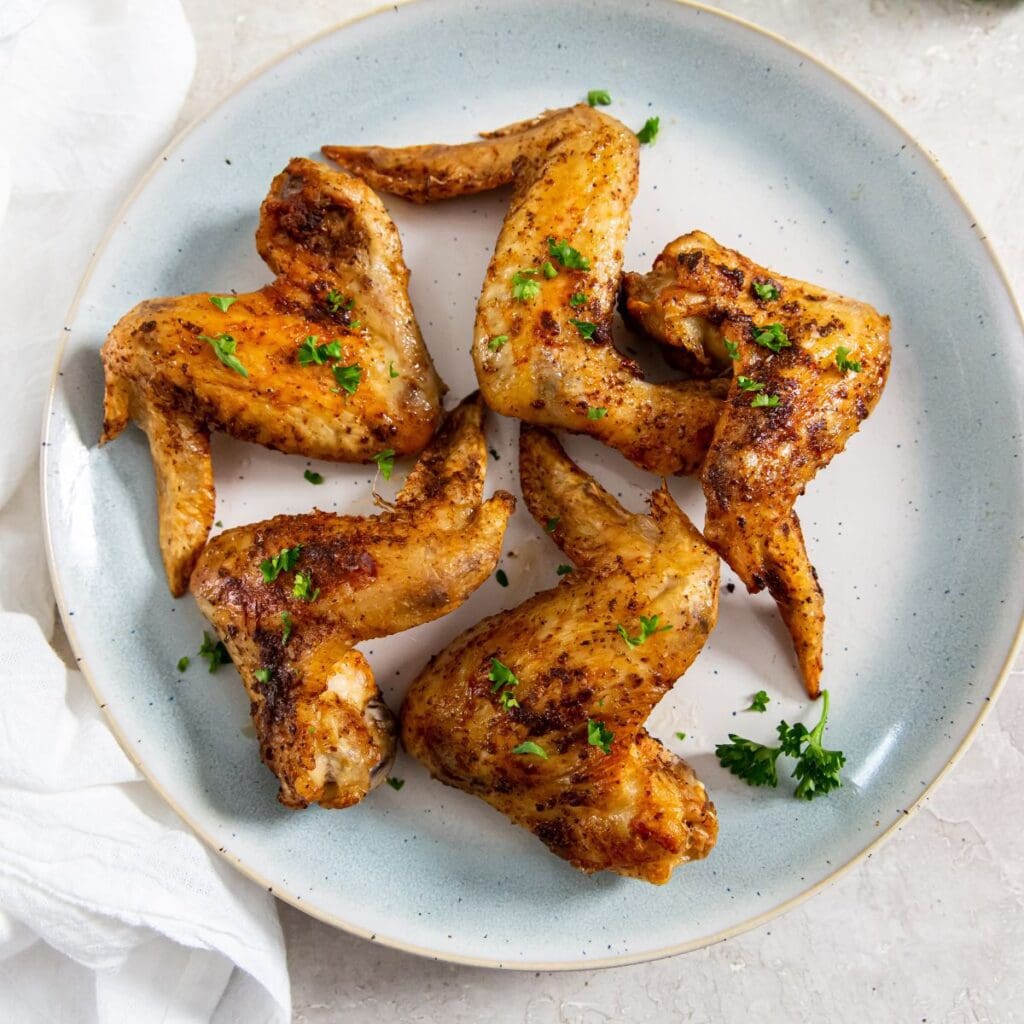 blue plate with chicken and parsley on it. White towel next to it.