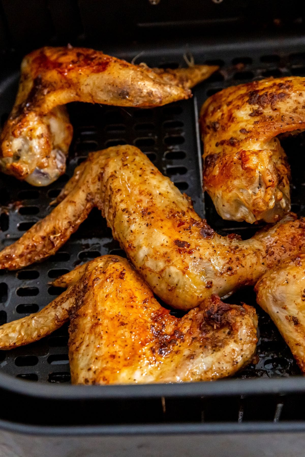 black air fryer basket with cooked chicken inside