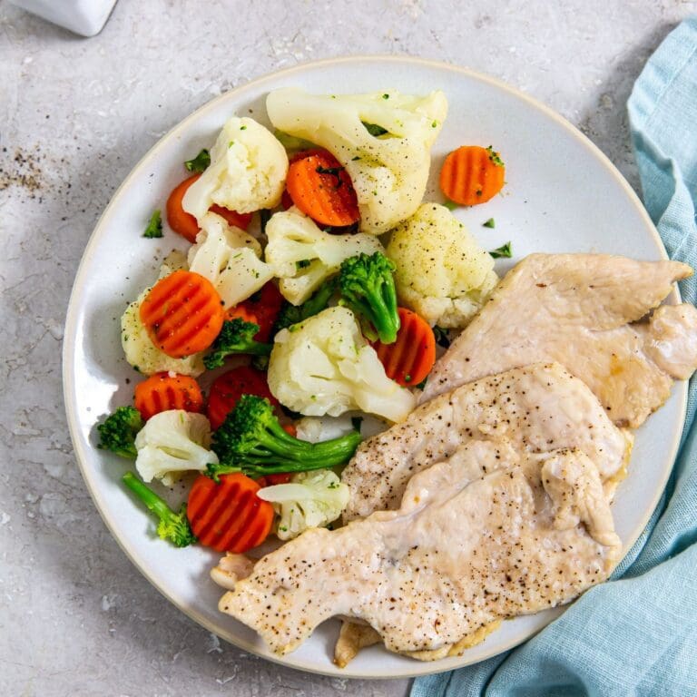 chicken breast cooked in an air fryer, served with vegetables.