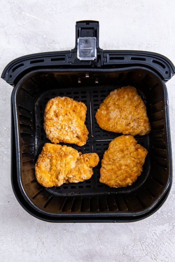 black air fryer basket with frozen chicken breast fillets