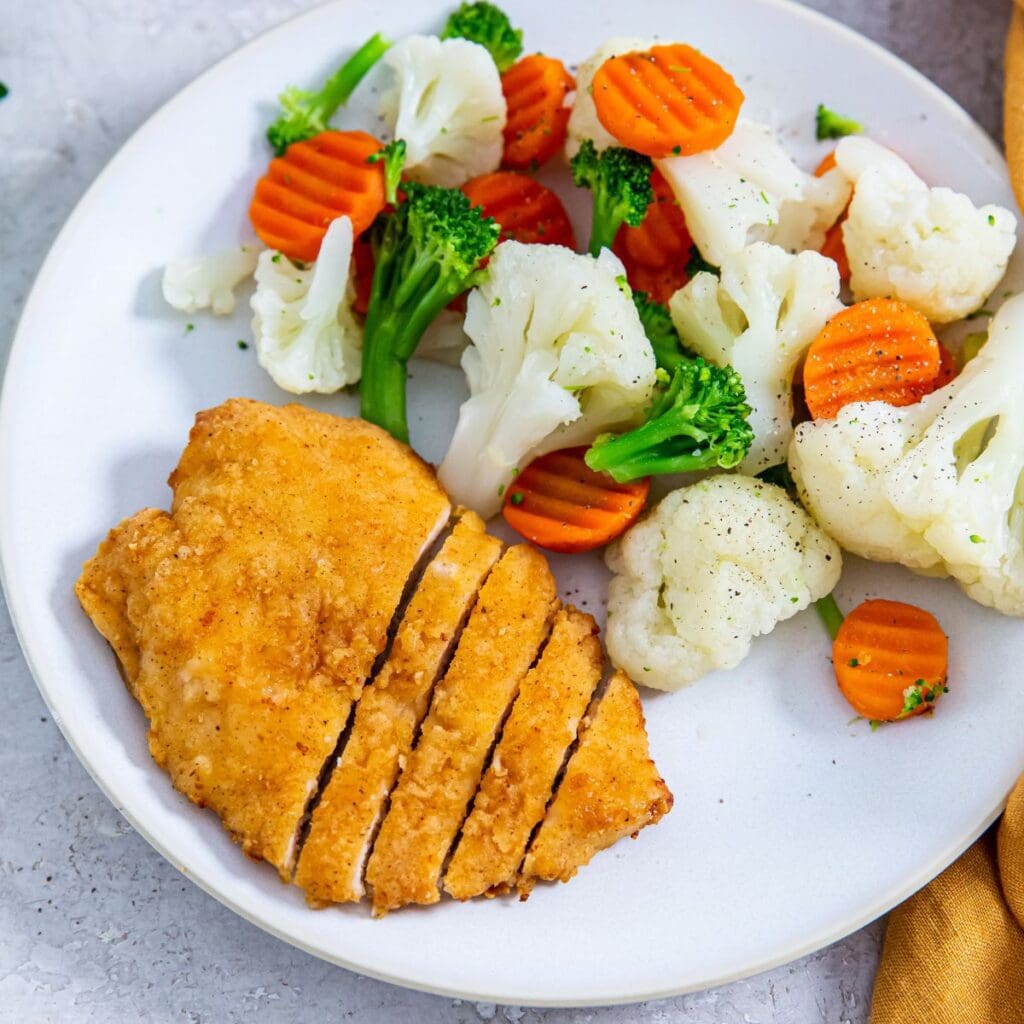 Chicken breast served with vegetables such as carrots and cauliflower, featuring Aldis Red Bag Chicken.