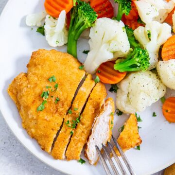 Aldis Red Bag Chicken breast on a plate with vegetables and a fork.