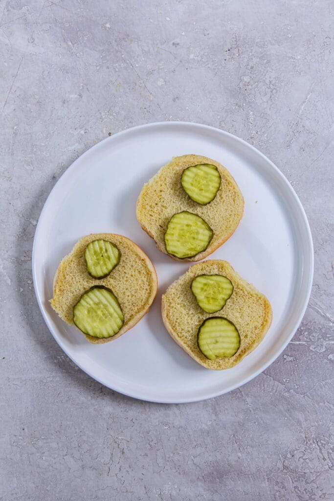 Three slices of bread with pickles on a plate.