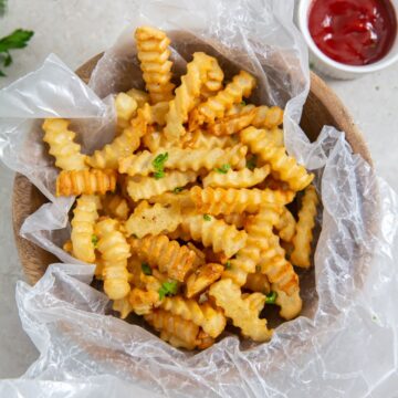 French fries cooked in an air fryer, served in a bowl with ketchup.