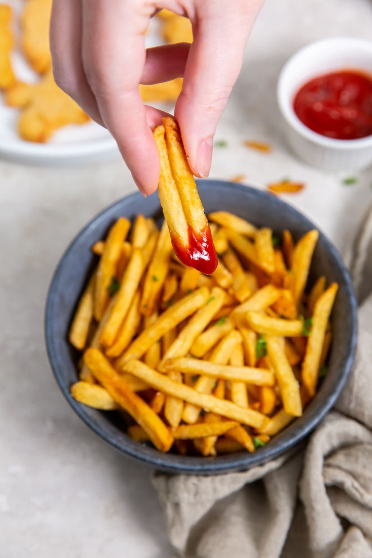 A hand holding French fries.