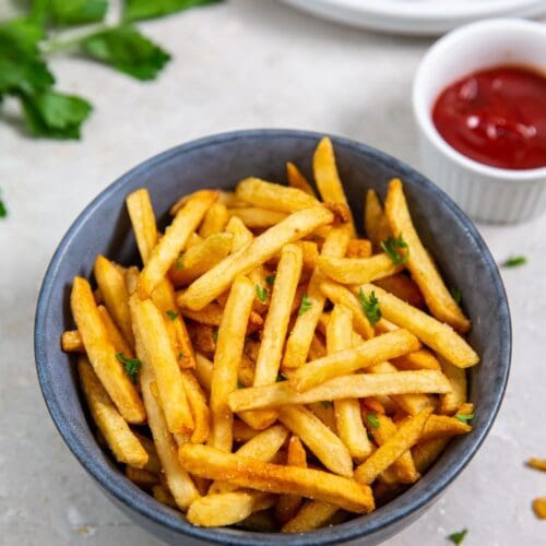 fries cooked in an air fryer and served in a bowl with ketchup.