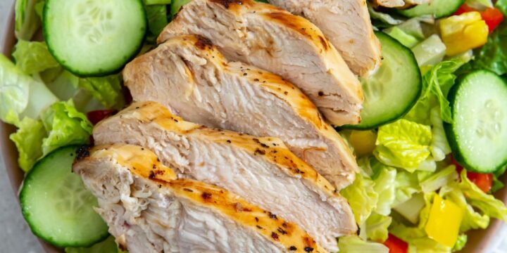 Grilled chicken salad on a plate with air-fried Italian chicken breast, cucumbers, and tomatoes.