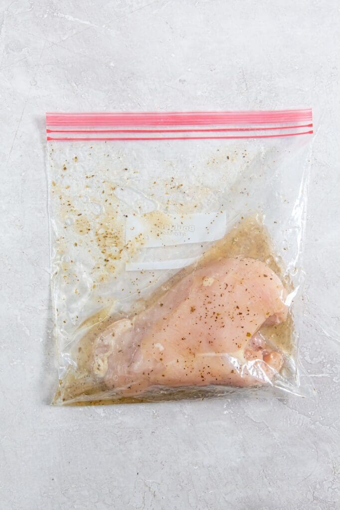 ziplock bag with chicken marinating in Italian dressing.