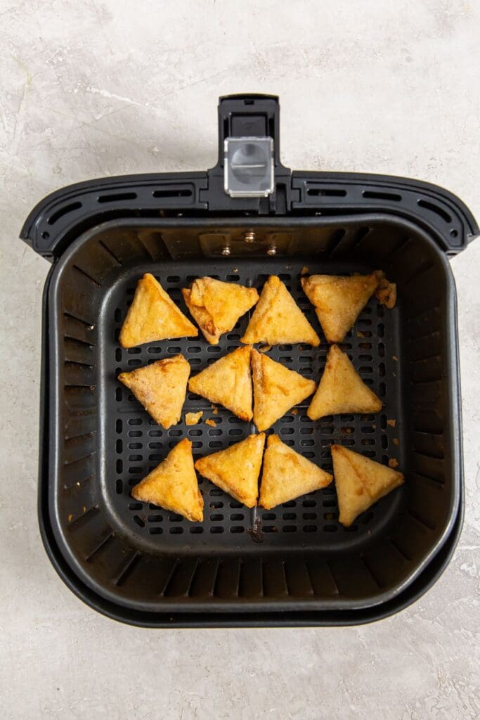 Black air fryer with raw chicken tikka samosas