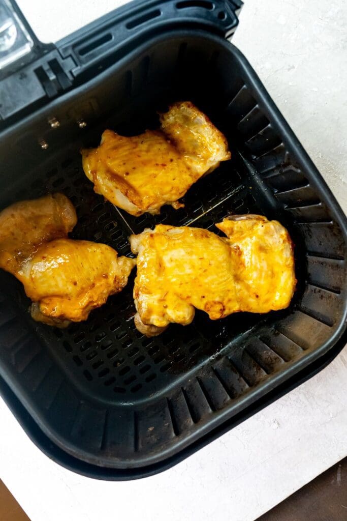 black air fryer basket with cooked chicken inside