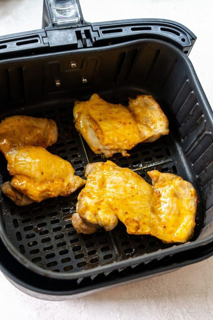 black air fryer basket with cooked chicken inside