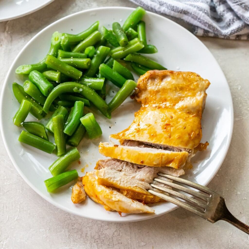 A plate with Air Fryer Peri Peri Chicken and green beans on it.