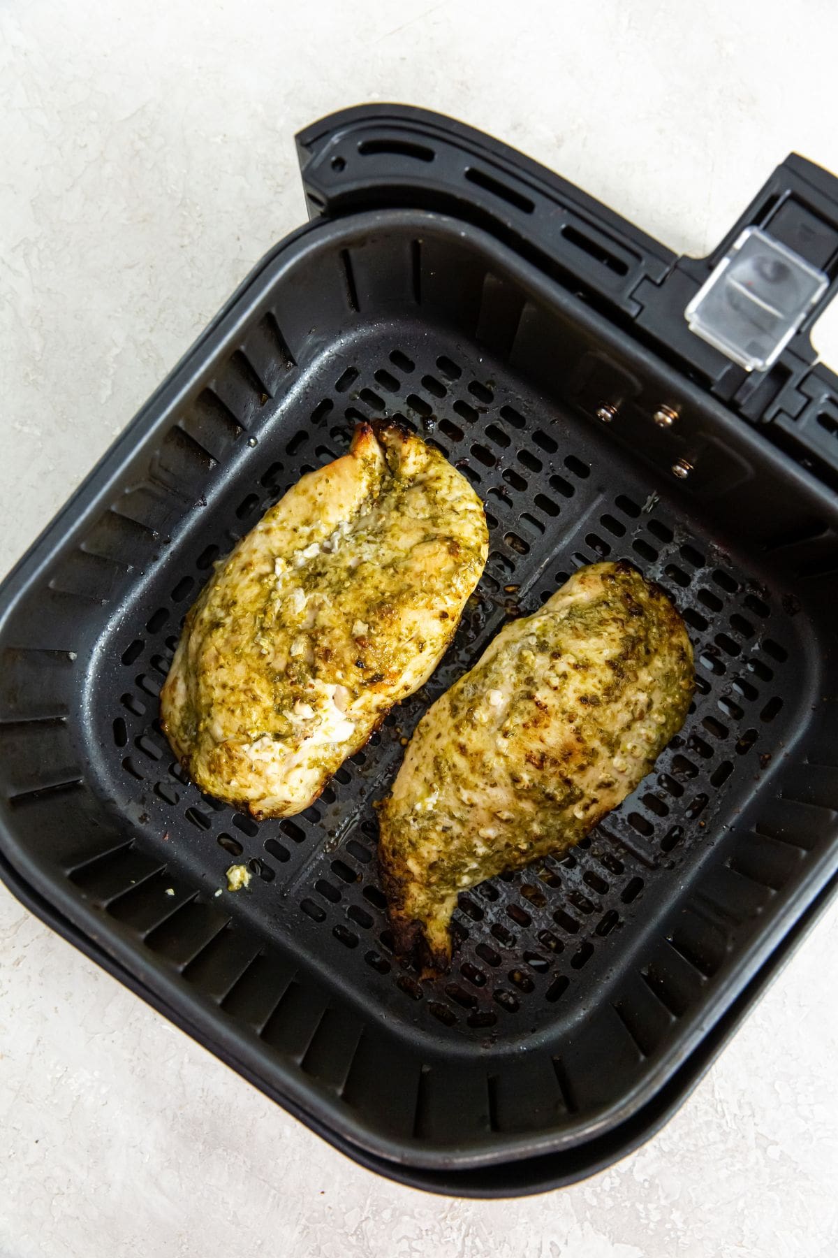 Air Fryer Pesto Chicken Breast black air fryer with cooked chicken inside