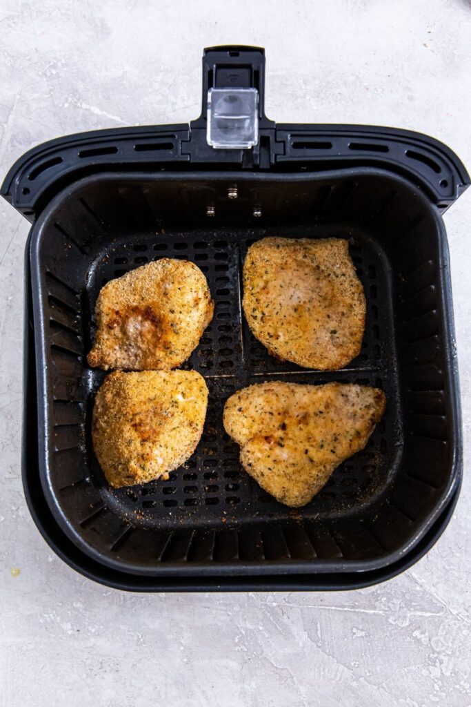 Air Fryer Chicken Cutlets black air fryer basket with cooked chicken inside