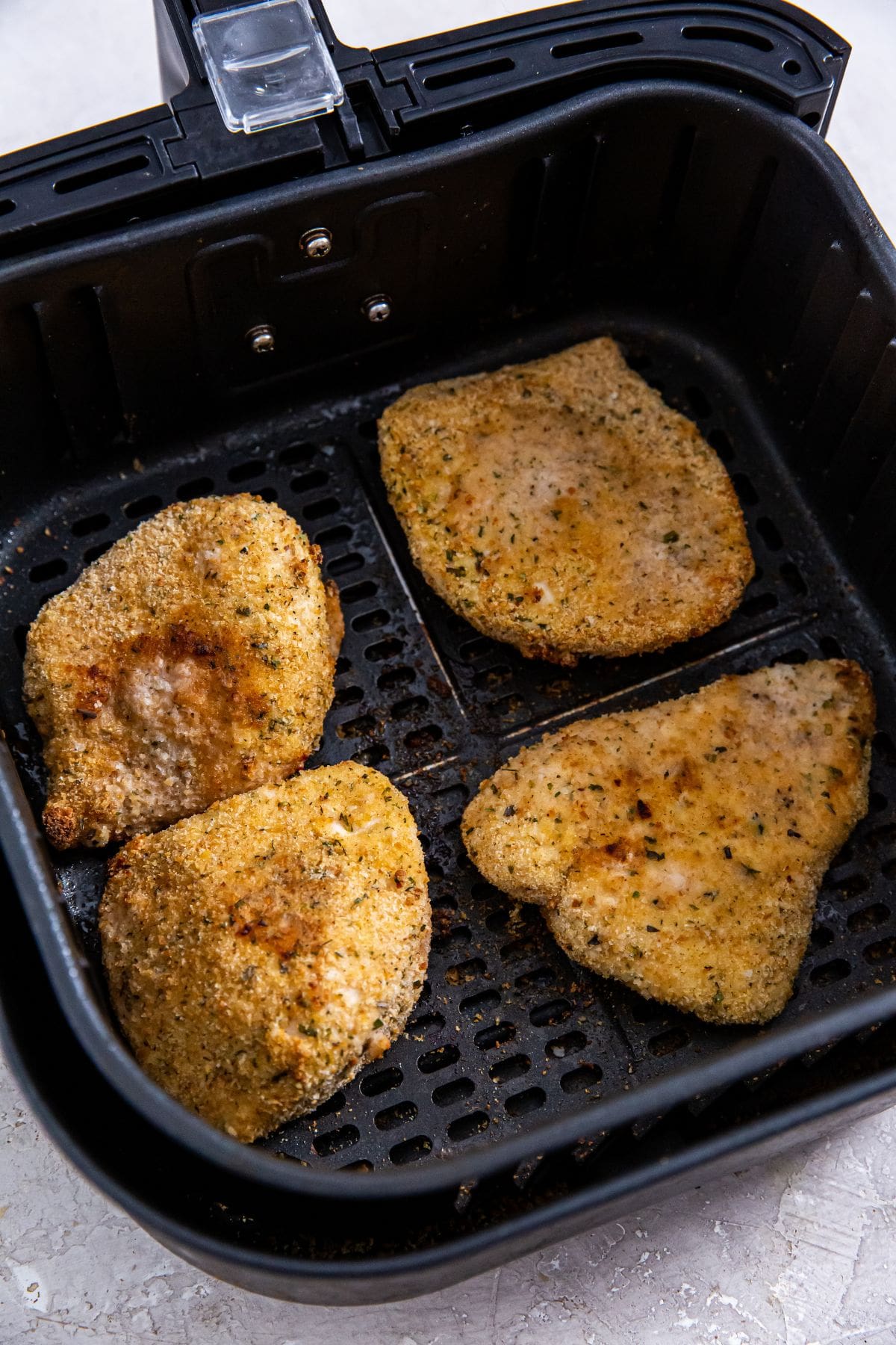 Air Fryer Chicken Cutlets black air fryer basket with cooked chicken cutlets inside