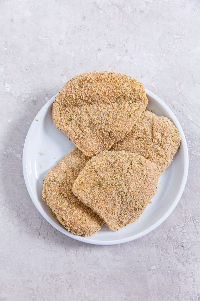 Air Fryer Chicken Cutlets white plate with raw chicken on it