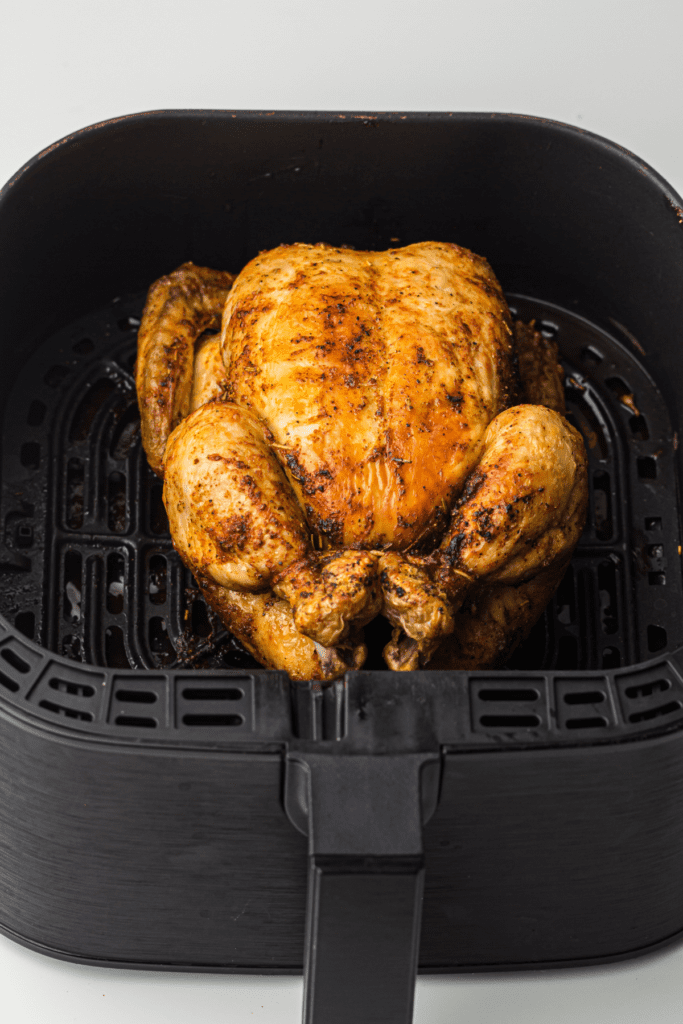 whole chicken in an air fryer basket.