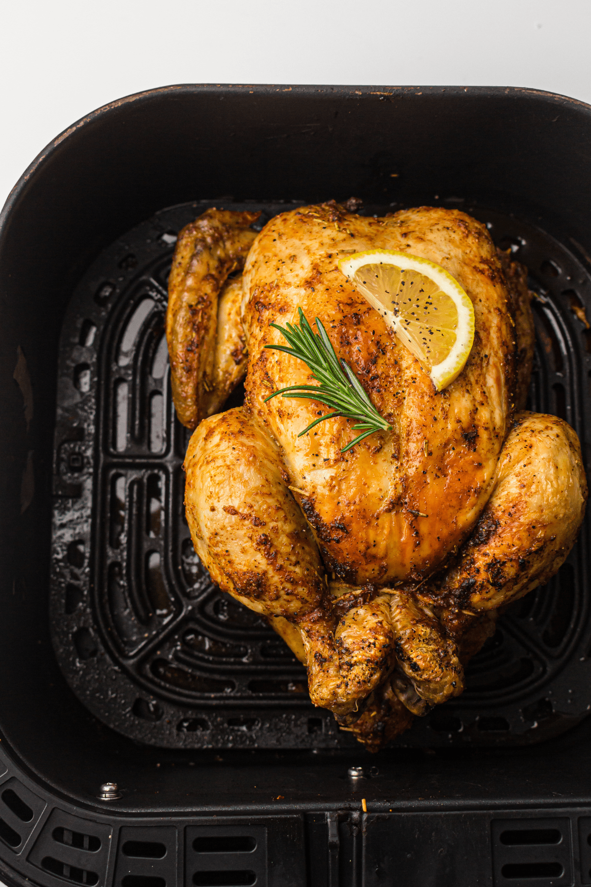 whole chicken in an air fryer basket.