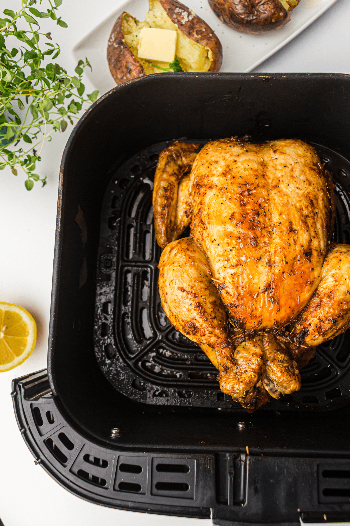 whole chicken in an air fryer basket.