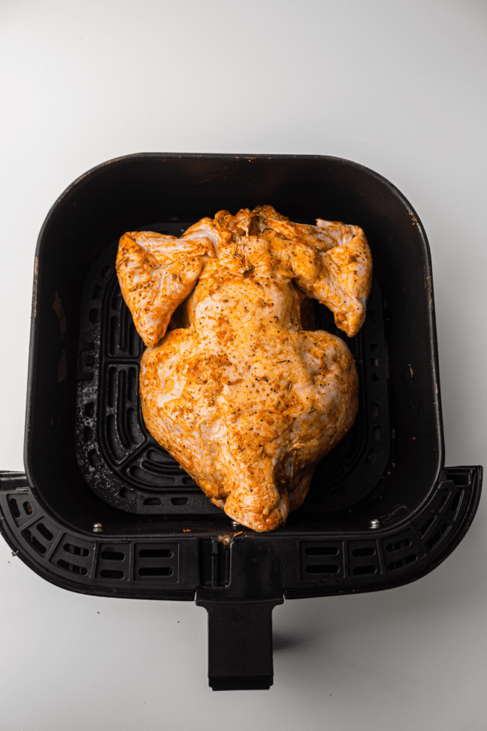 Raw chicken inside a black air fryer basket