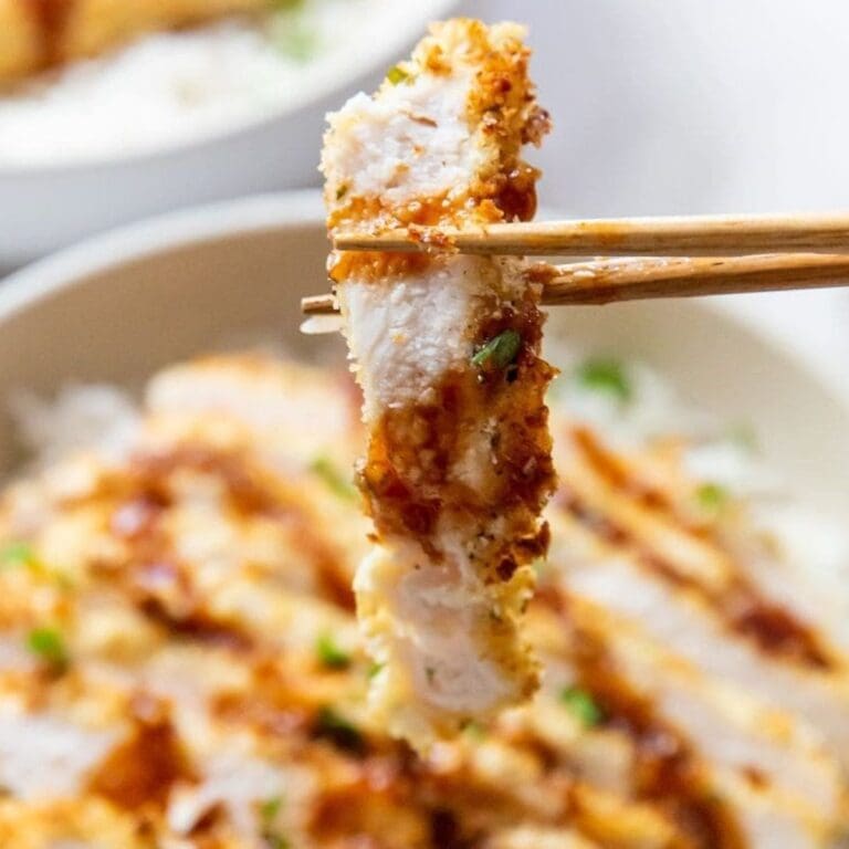 Air Fryer Chicken Recipes That Make Even Bad Days Good Close Up of Katsu Chicken in Chopsticks Above a Bowl of White Rice