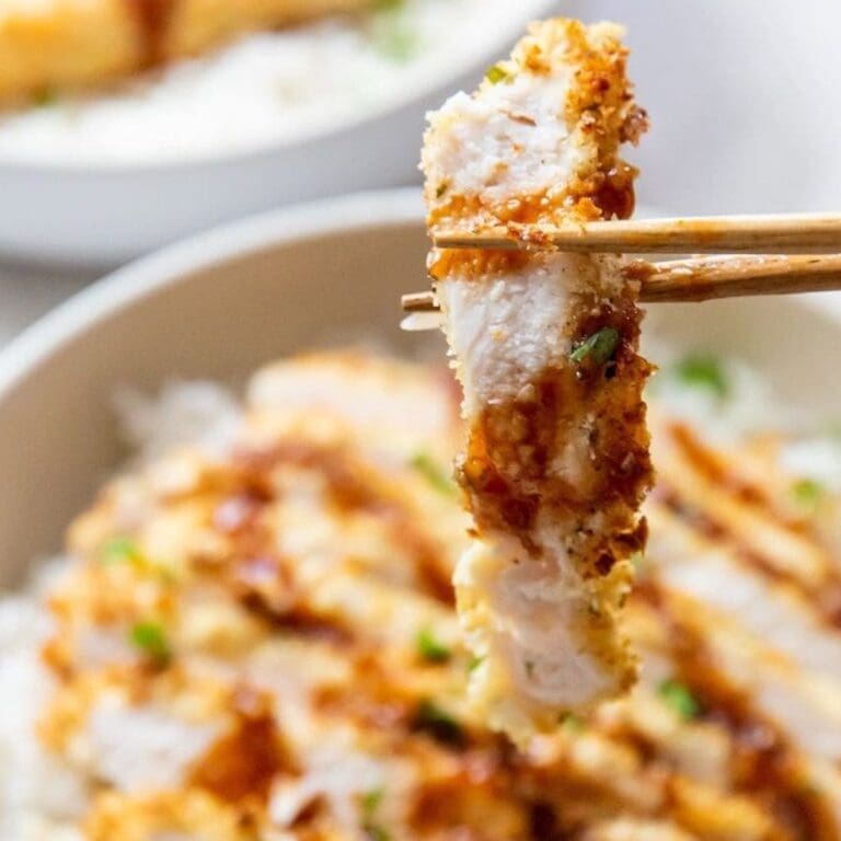 Chicken Air Fryer Recipes That'll Make Your Friends Jealous Close Up of a Piece of Katsu Chicken In Between Two Chopsticks