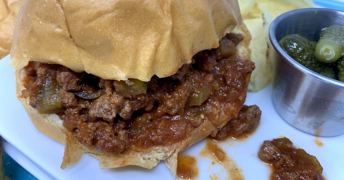 Midweek Meal Plan Close Up of a Sloppy Joe with a Small Metal Ramekin of Dill Pickles