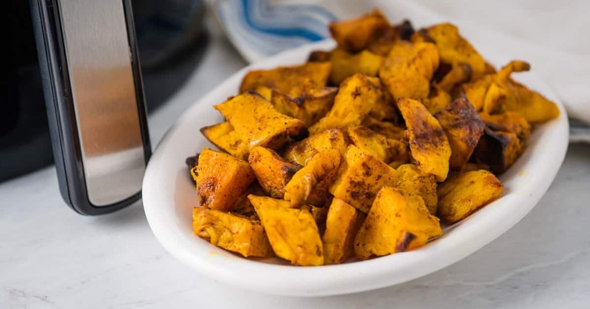 Mouthwatering Sides a Bowl of Air Fryer Butternut Squash on a Counter Top in Front of an Air Fryer