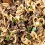 A close-up of a plate of beef stroganoff consisting of beef, mushrooms, and egg noodles, garnished with chopped parsley—a perfect addition to your midweek meal plan.