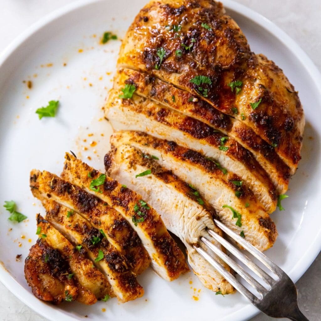 Chicken Air Fryer Recipes Close Up of Sliced Cooked Chicken on a White Plate with a Fork