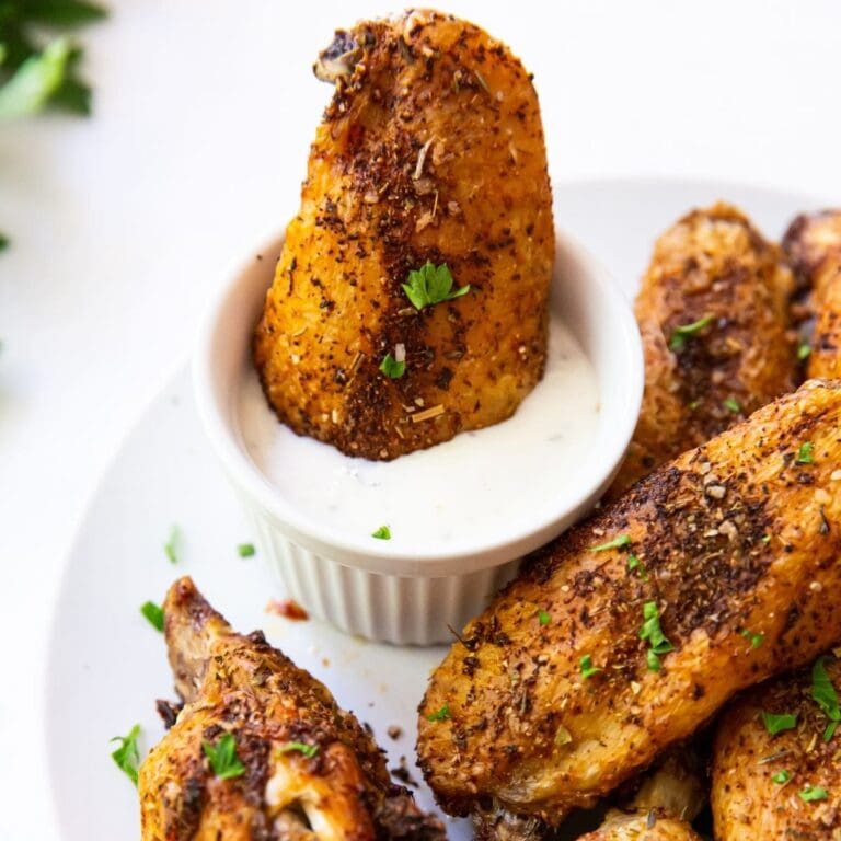 Christmas Party Air Fryer Recipes Close Up of Dry Rubbed Wings With One in a Small Bowl of Ranch Dressing