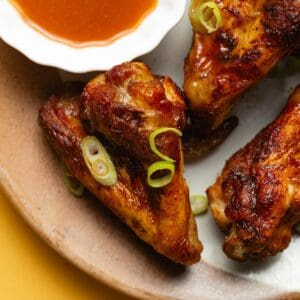 Easy Air Fryer Buffalo Wings Recipe Close Up of Wings on a Plate with a Small Bowl of Buffalo Sauce