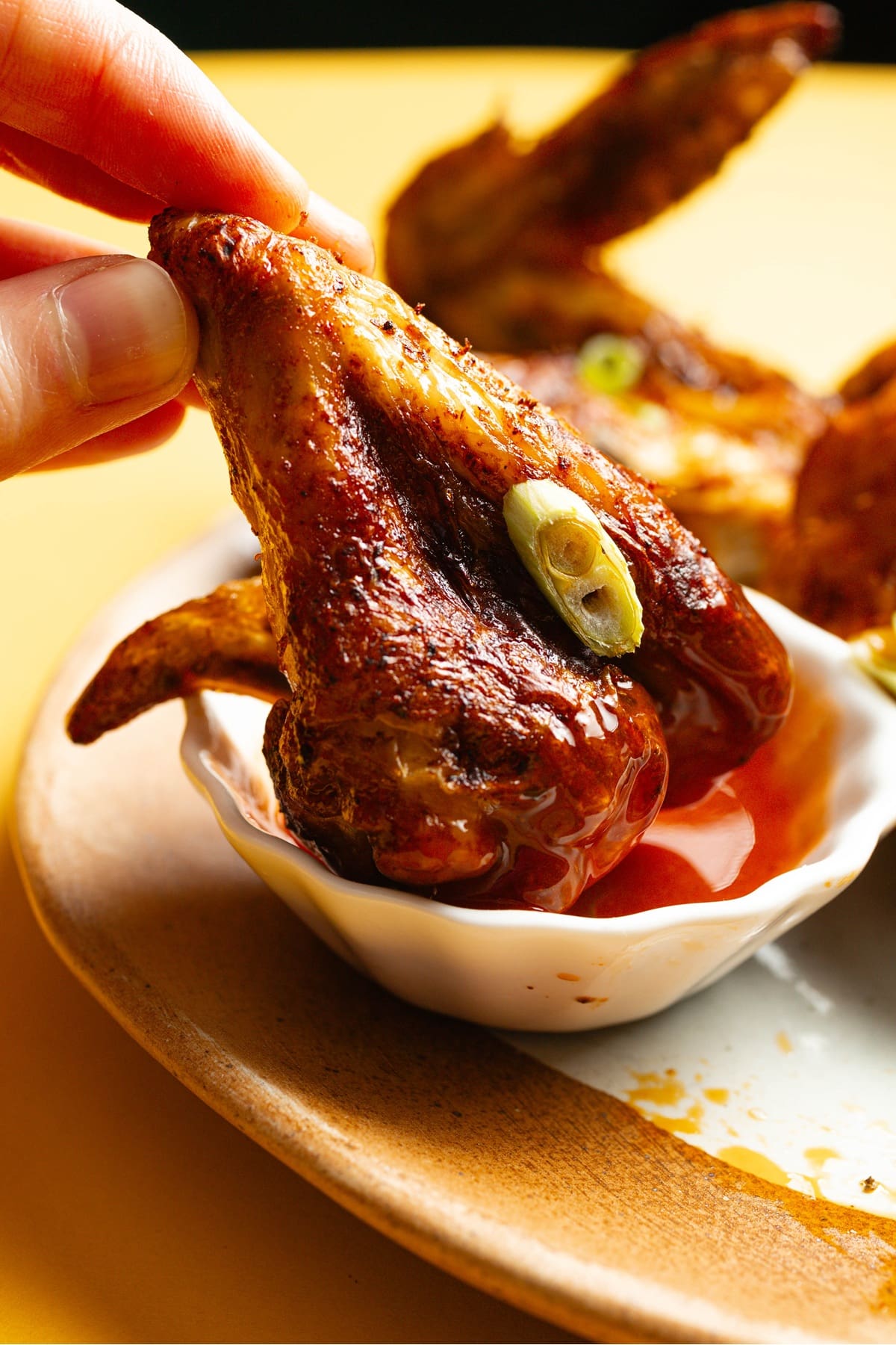 Easy Air Fryer Buffalo Wings Close Up of a Wing Being Dipped in a Small Bowl of Buffalo Sauce