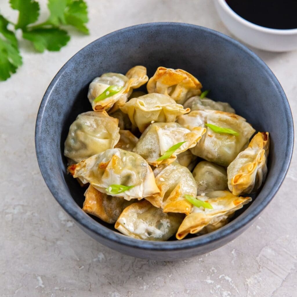 New Year's Eve Air Fryer Party Recipes Close Up of a Bowl of Potstickers with a Side of Dipping Sauce