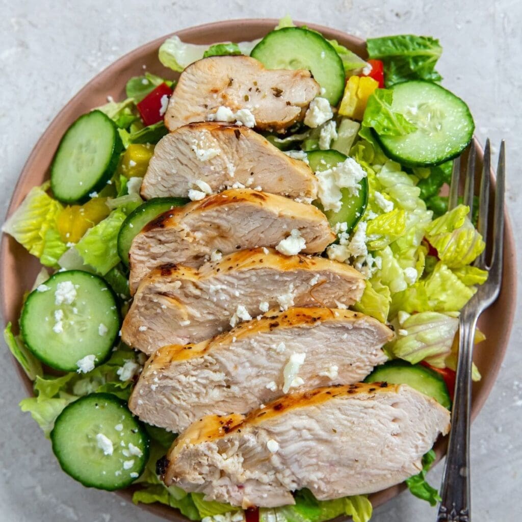 Weight Loss Air Fryer Chicken Recipes Overhead View of a Salad Topped with Sliced Chicken and Cucumber