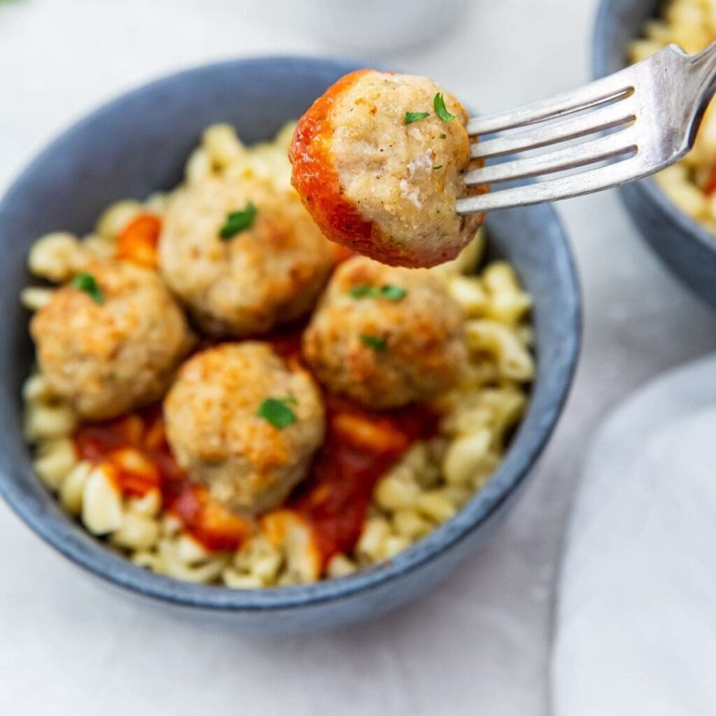 Date Night Air Fryer Recipes A Meatball on a Fork Hovering Above a Bowl of Meatballs and Pasta