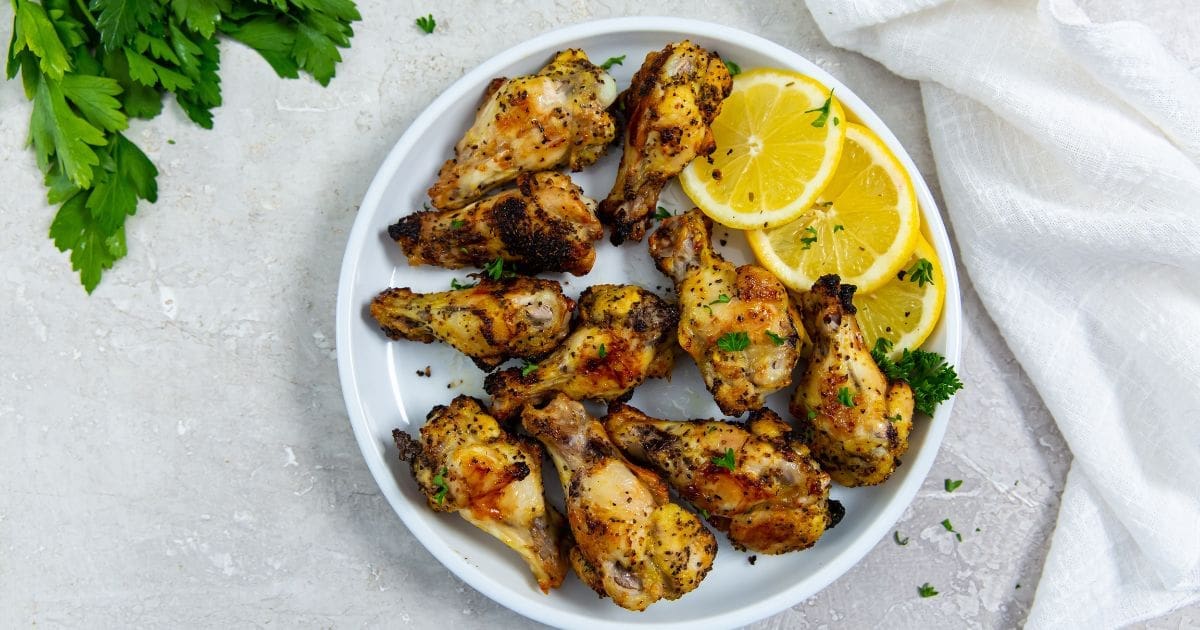 St. Patricks Day Air Fryer Recipes a Plate of Delicious Air Fryer Lemon Pepper Chicken Wings Garnished with Thinly Sliced Lemon