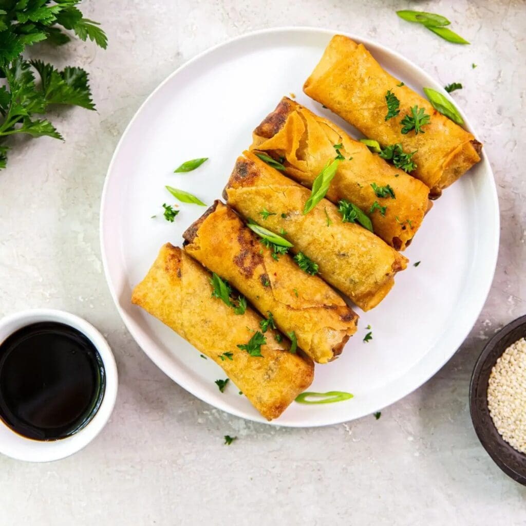 Super Bowl Air Fryer Snacks a Plate with 5 Egg Rolls on it Next to a Ramekin of Dipping Sauce