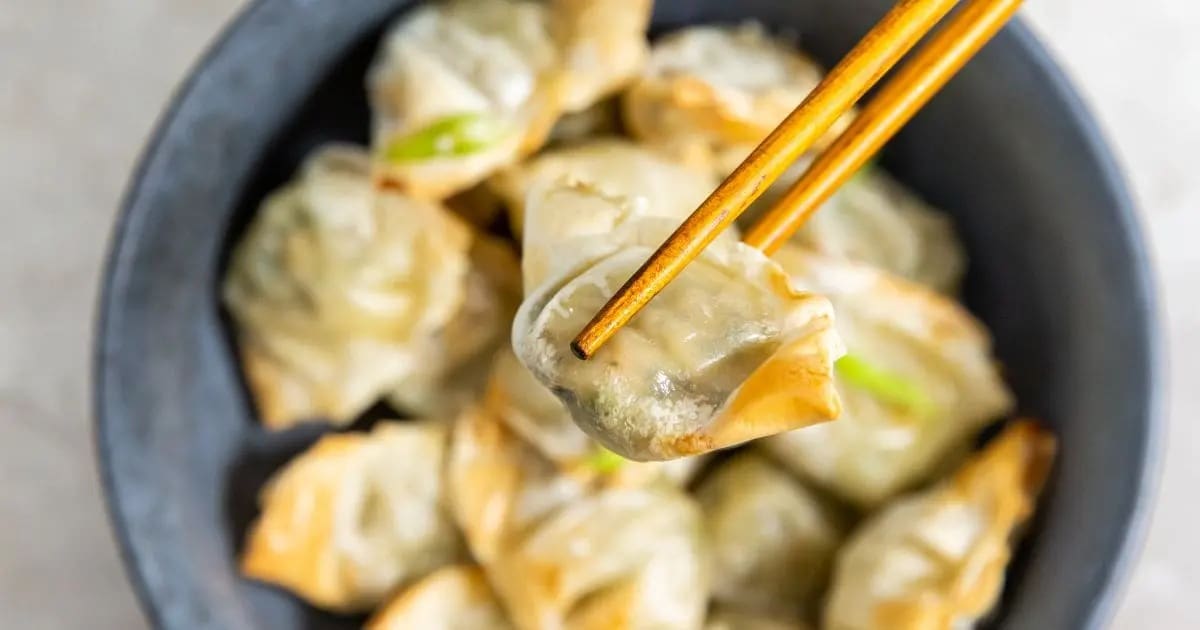 Super Bowl Air Fryer Snacks Close Up of a Won Ton Held with Chopsticks Above a Bowl of Won Tons