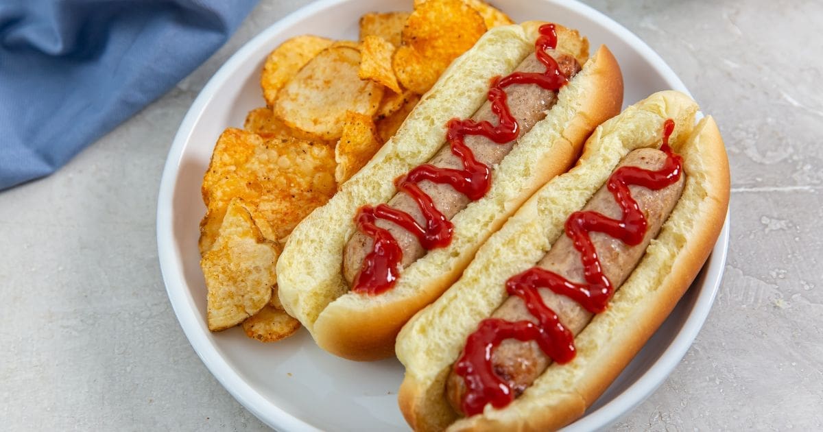 Easy Summer Air Fryer Recipes Easy Air Fryer Trader Joe’s Sweet Apple Chicken Sausage in Hot Dog Buns with Ketchup and BBQ Chips on a Plate