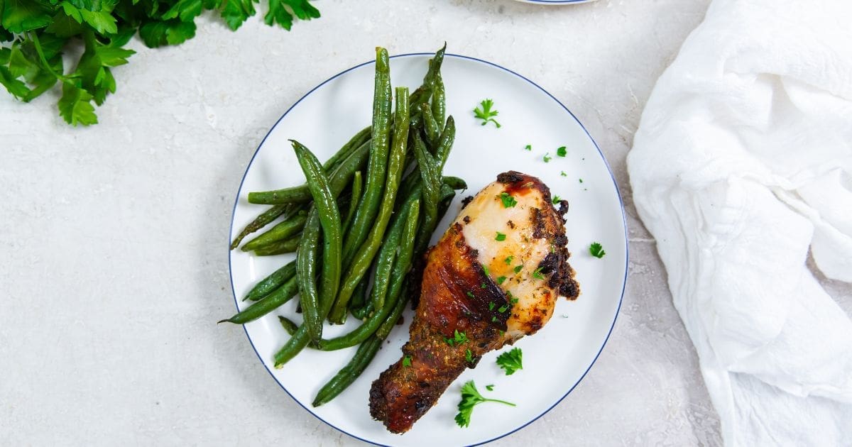 Must Make Memorial Day Recipes in your Air Fryer Close Up of Crispy Air Fryer Ranch Chicken Legs on a Plate with Green Beans