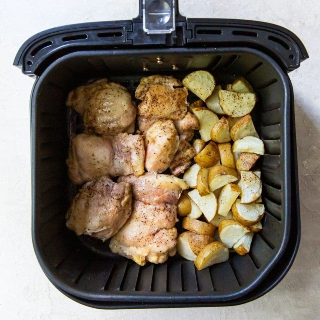 Chicken Air Fryer Recipes So Good an Air Fryer Basket Filled with Chicken Thighs and Potatoes