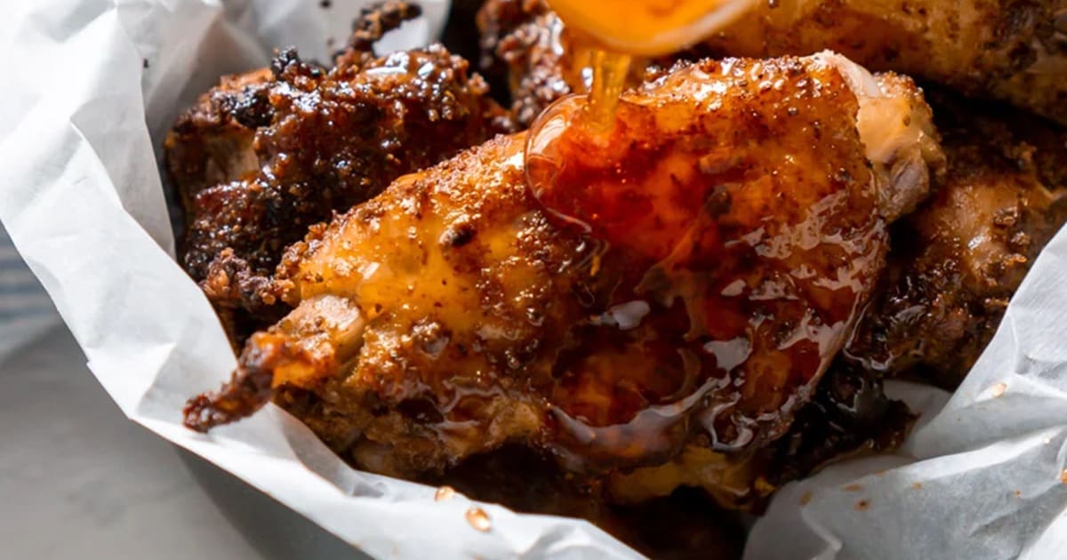 Air Fryer Chicken Wings for Your Summer BBQ Close Up of Old Bay Wings Being Drizzled with Honey from a Spoon
